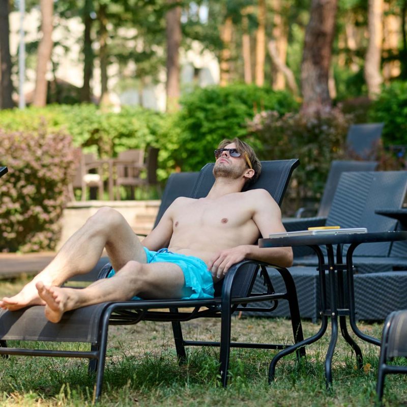 Sunbathing. Young man in blue shorts sunbathing and looking relaxed